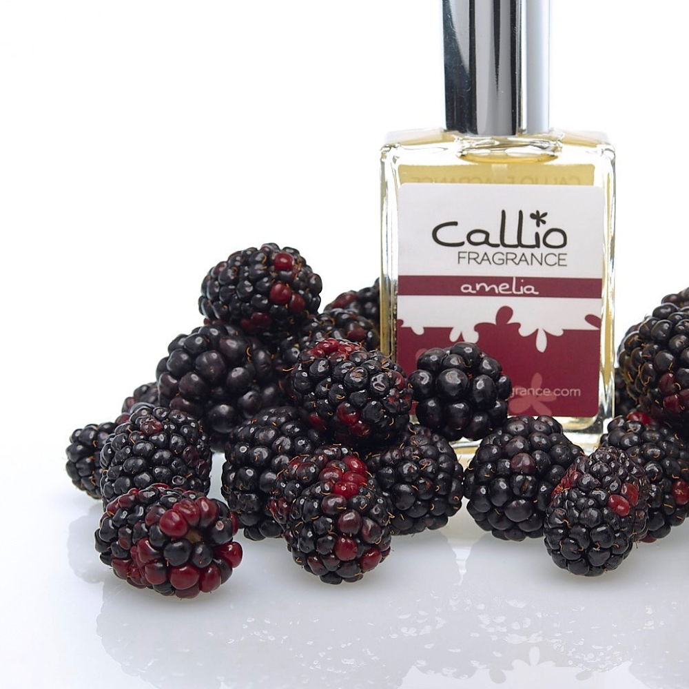 One ounce bottle of Amelia on a white background surrounded by blackberries.