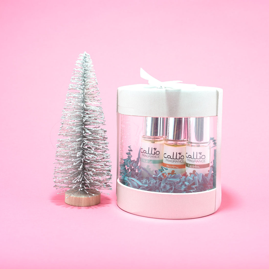 Perfume Trio Gift Set on a light pink background with a silver brush tree.