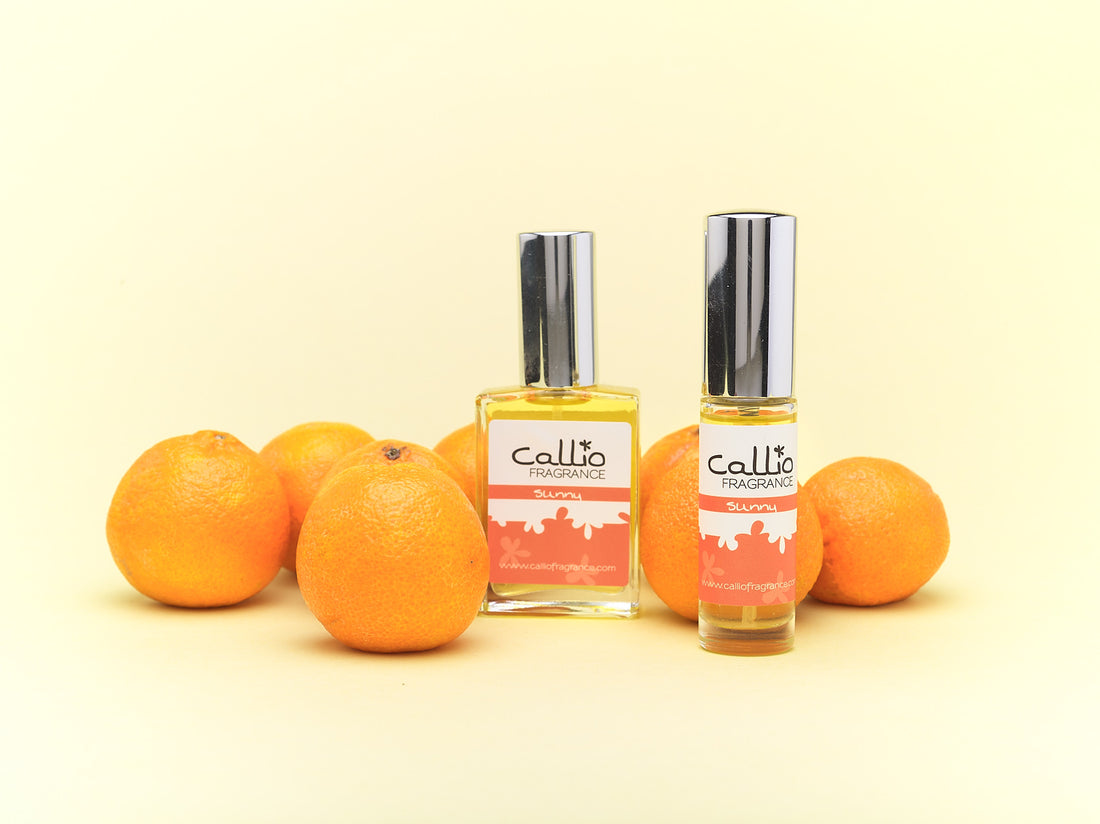 Sunny Travel Perfume and one-ounce bottles on a yellow background with mandarin oranges.