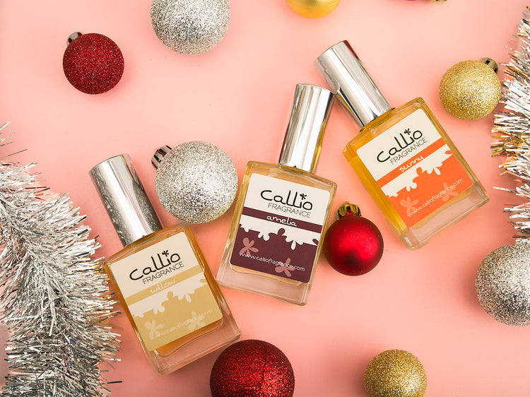 One-ounce bottles of Willow, Amelia, and Sunny on a ink background with silver tinsel and Christmas ornaments by Callio Fragrance.