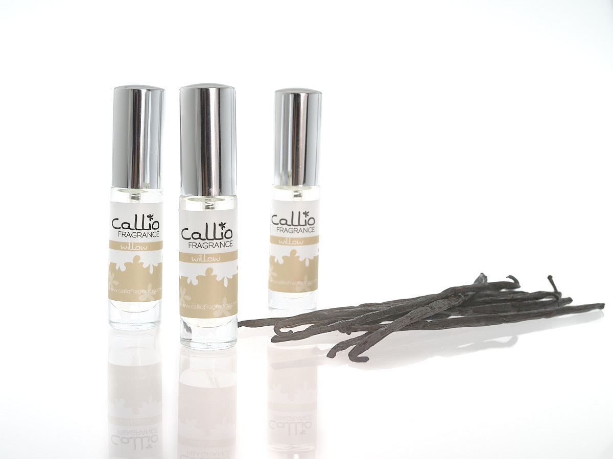 Three bottles of Willow Travel perfume with vanilla beans on a white background.